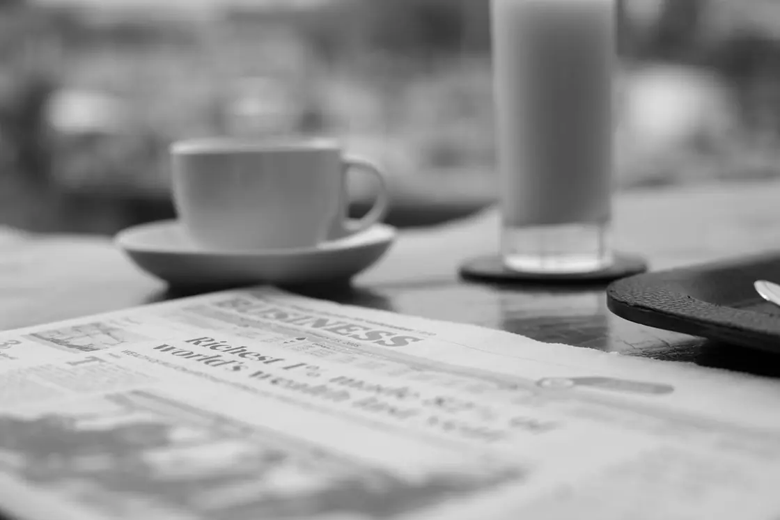 A coffee cup beside a newspaper business section